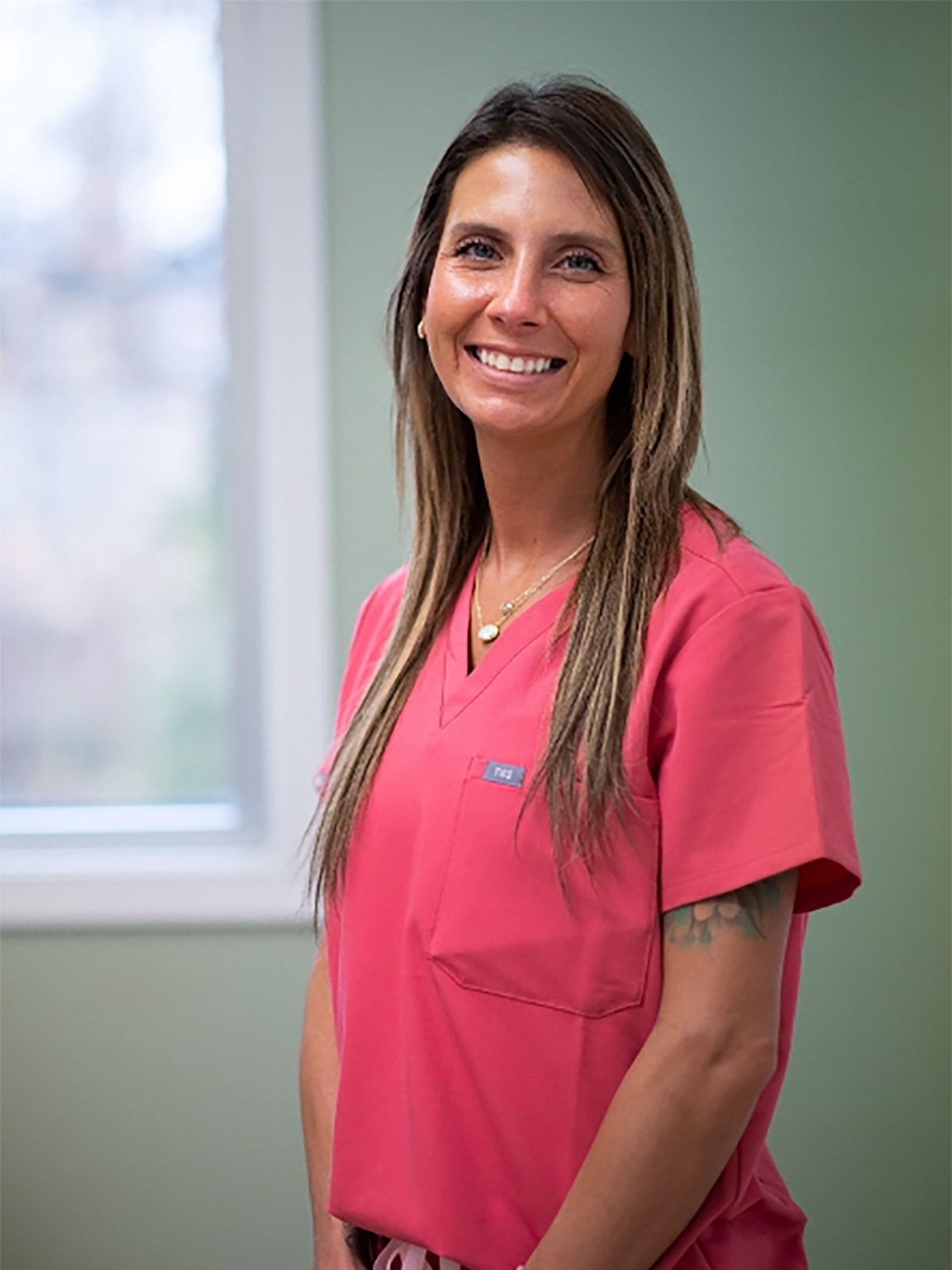 Smiling woman in pink medical scrubs.