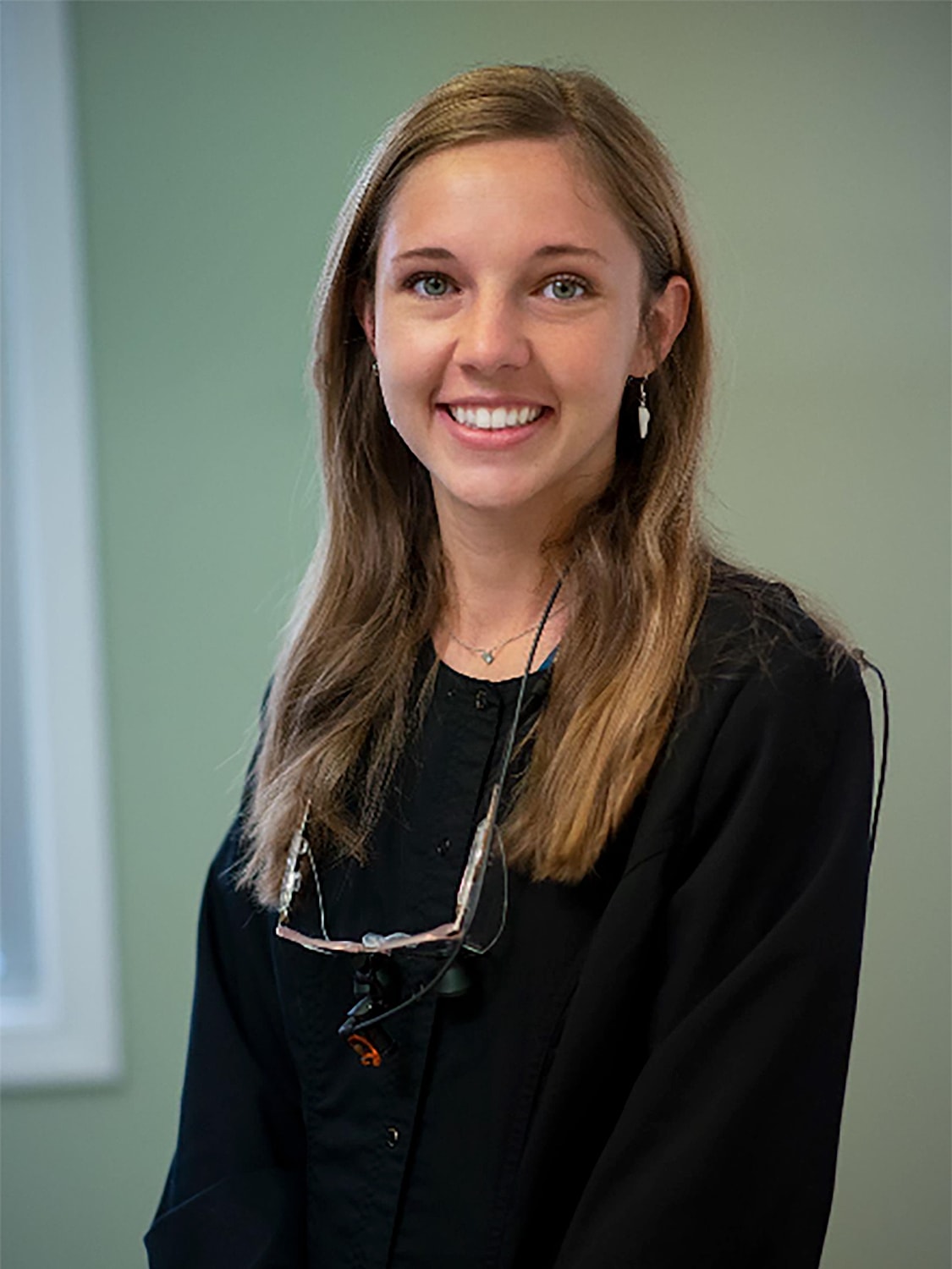 Smiling woman wearing glasses in professional attire.
