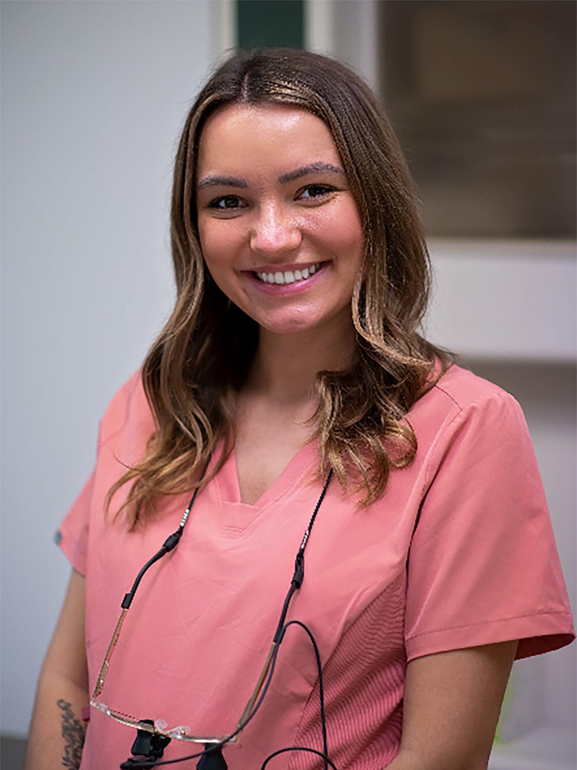 Smiling healthcare worker in pink scrubs.
