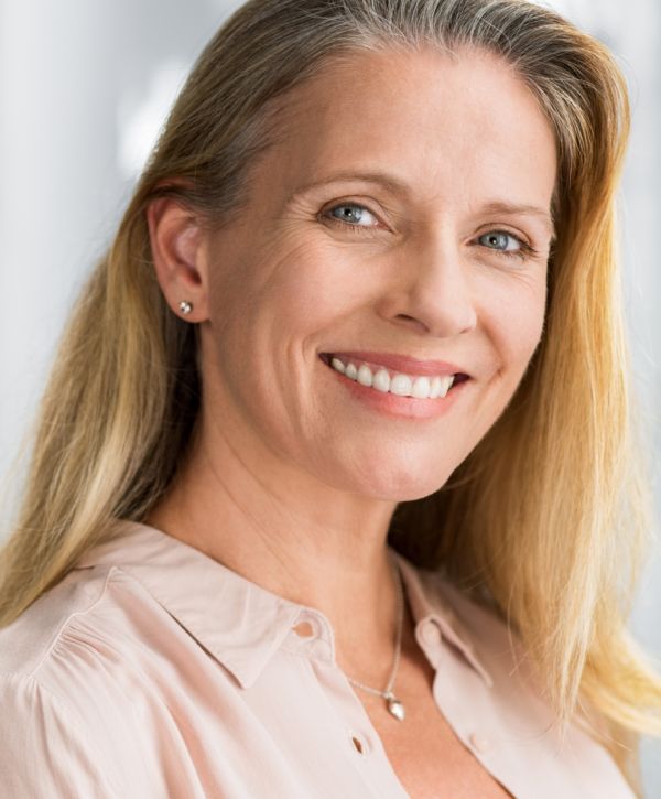 dental bridge patient model smiling broadly in a pink button up