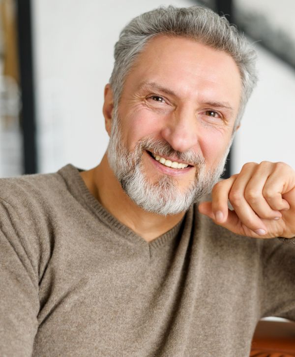 dental implant patient model smiling wearing a brown cashmere sweater